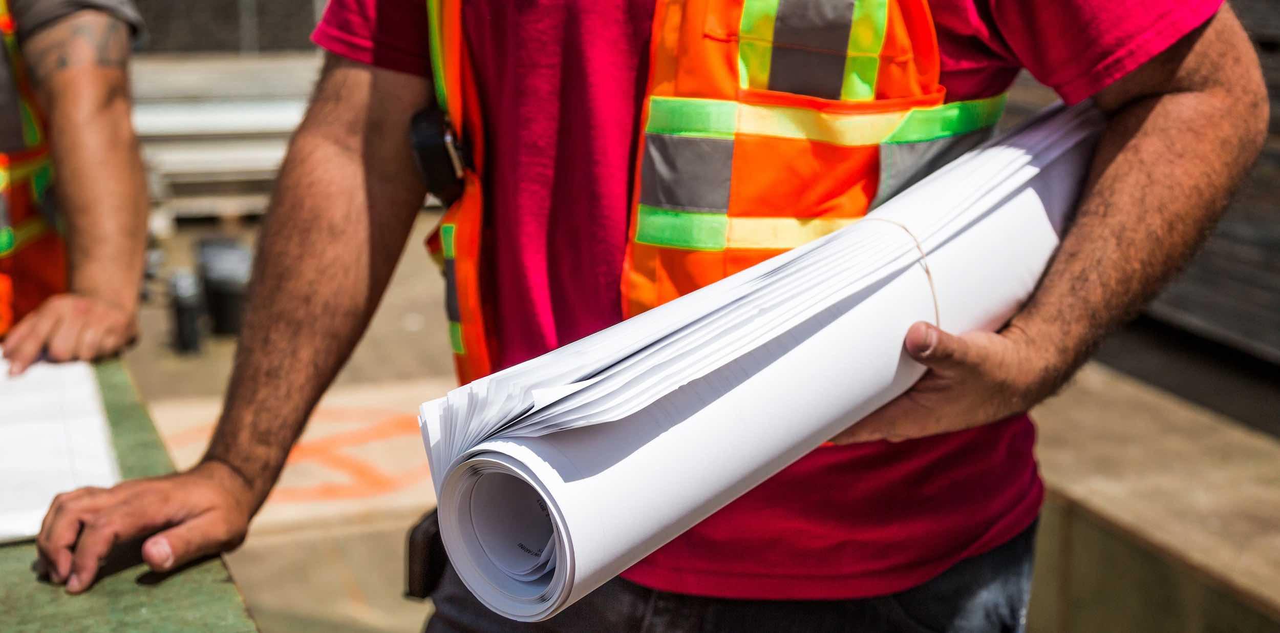 construction worker with rolled-up blueprints